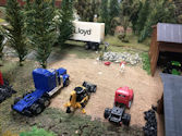 Model train enthusiasts working on a detailed mountain layout with a winding railway track.