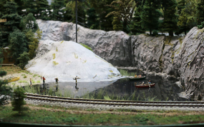 Model train layout with a scenic lake, fishermen, and boats at Pine Ridge Model Railroaders Club.