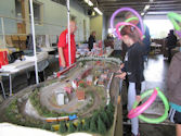 A train depot with multiple model locomotives parked at maintenance sheds.