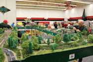 A model railway featuring a train depot, locomotives, and workers maintaining the tracks.